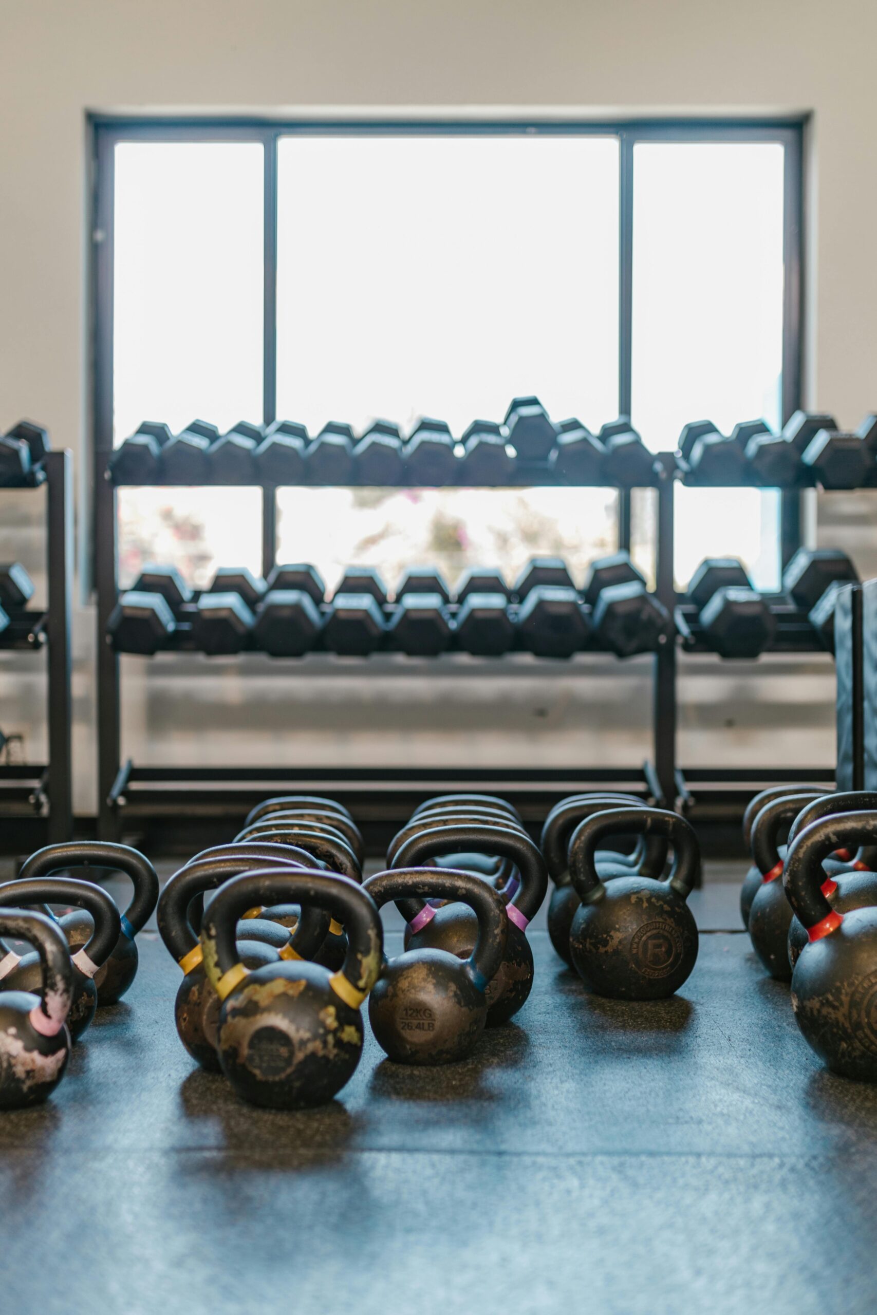 A well-lit gym with kettlebells and dumbbells arranged neatly, ideal for workout inspiration.